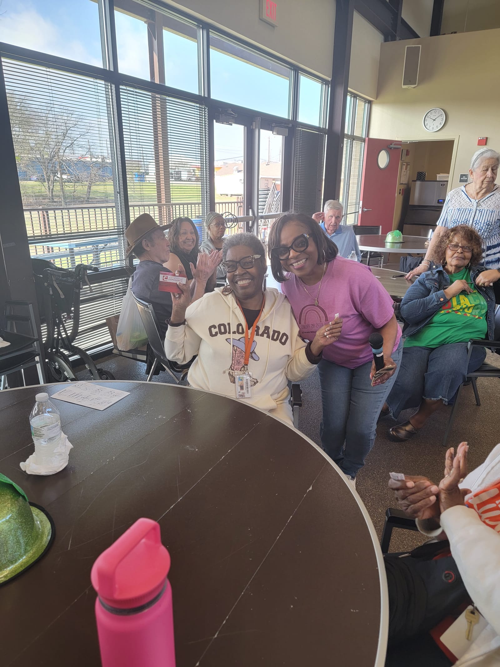 Seniors smiling and waving from their table at a Silver Saints gathering