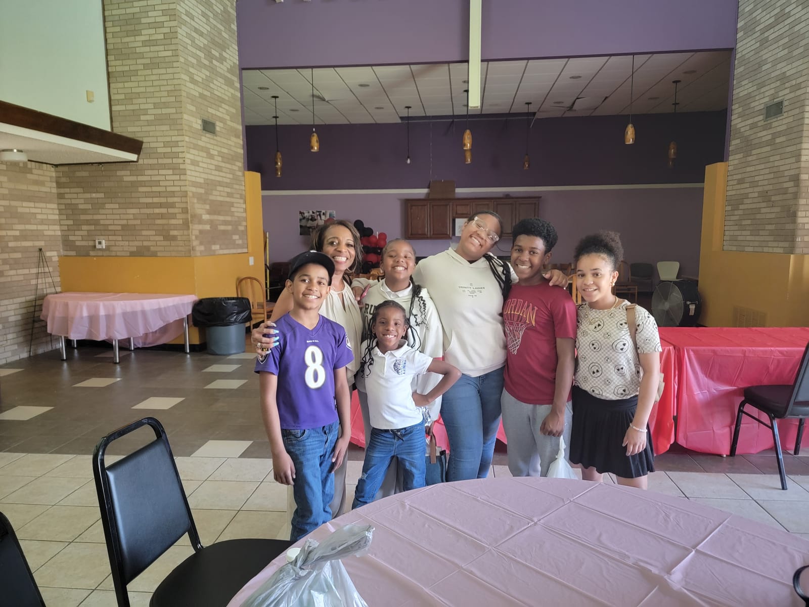 Young people and a Silver Saints volunteer smiling together in a community hall