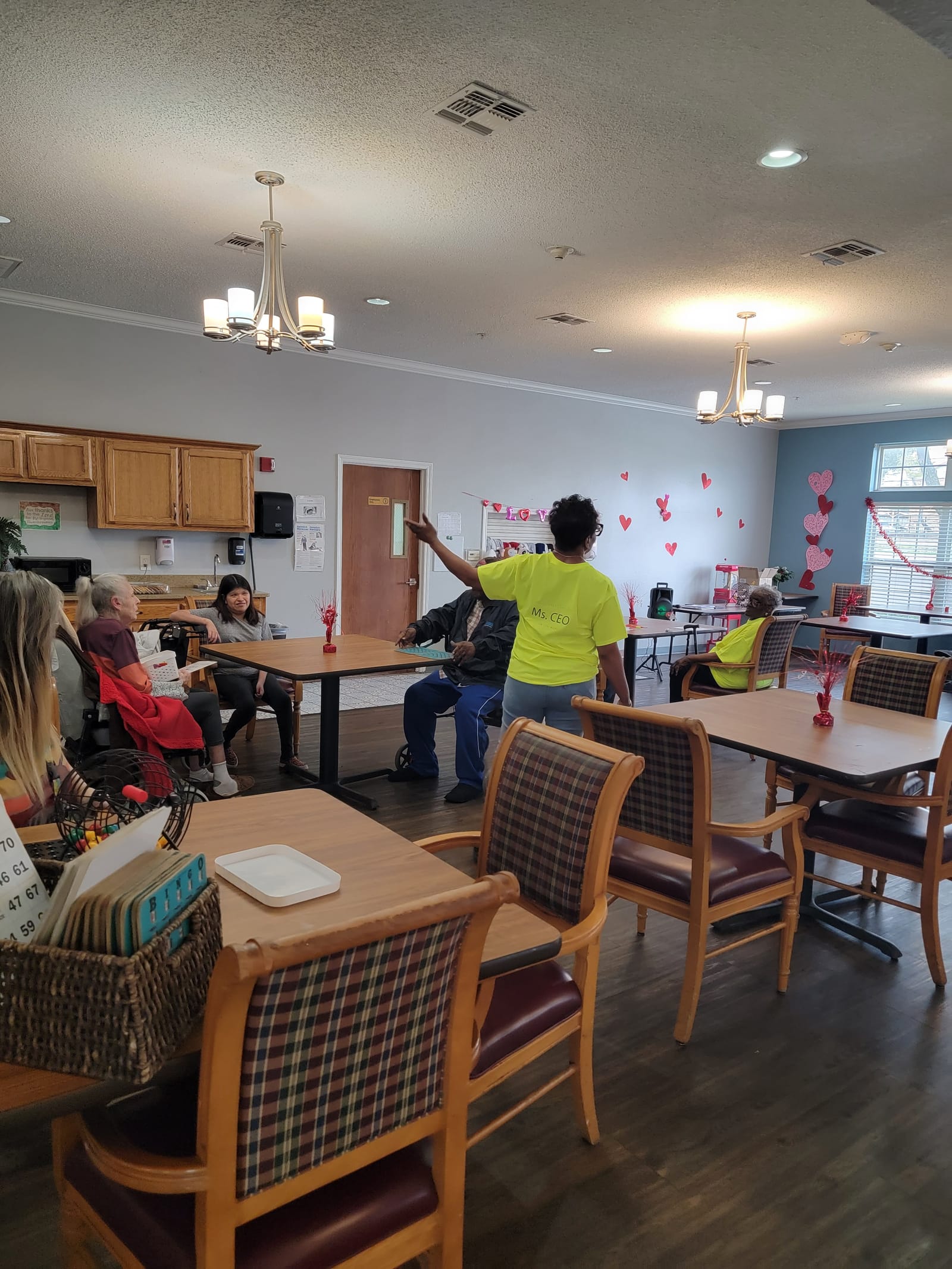 A senior playing bingo with a volunteer standing by