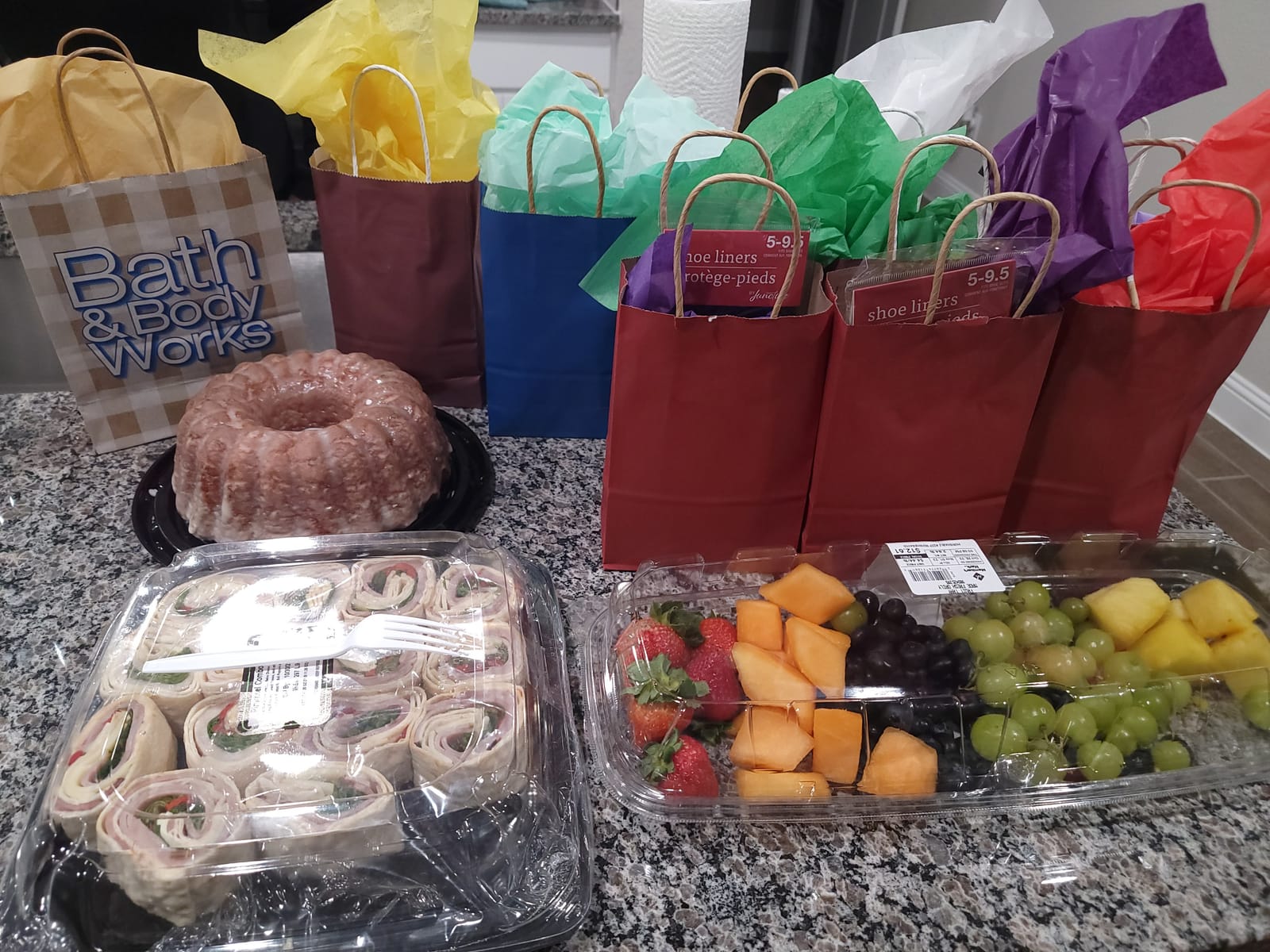 Gift bags, a bundt cake and fruit trays ready for a Silver Saints event
