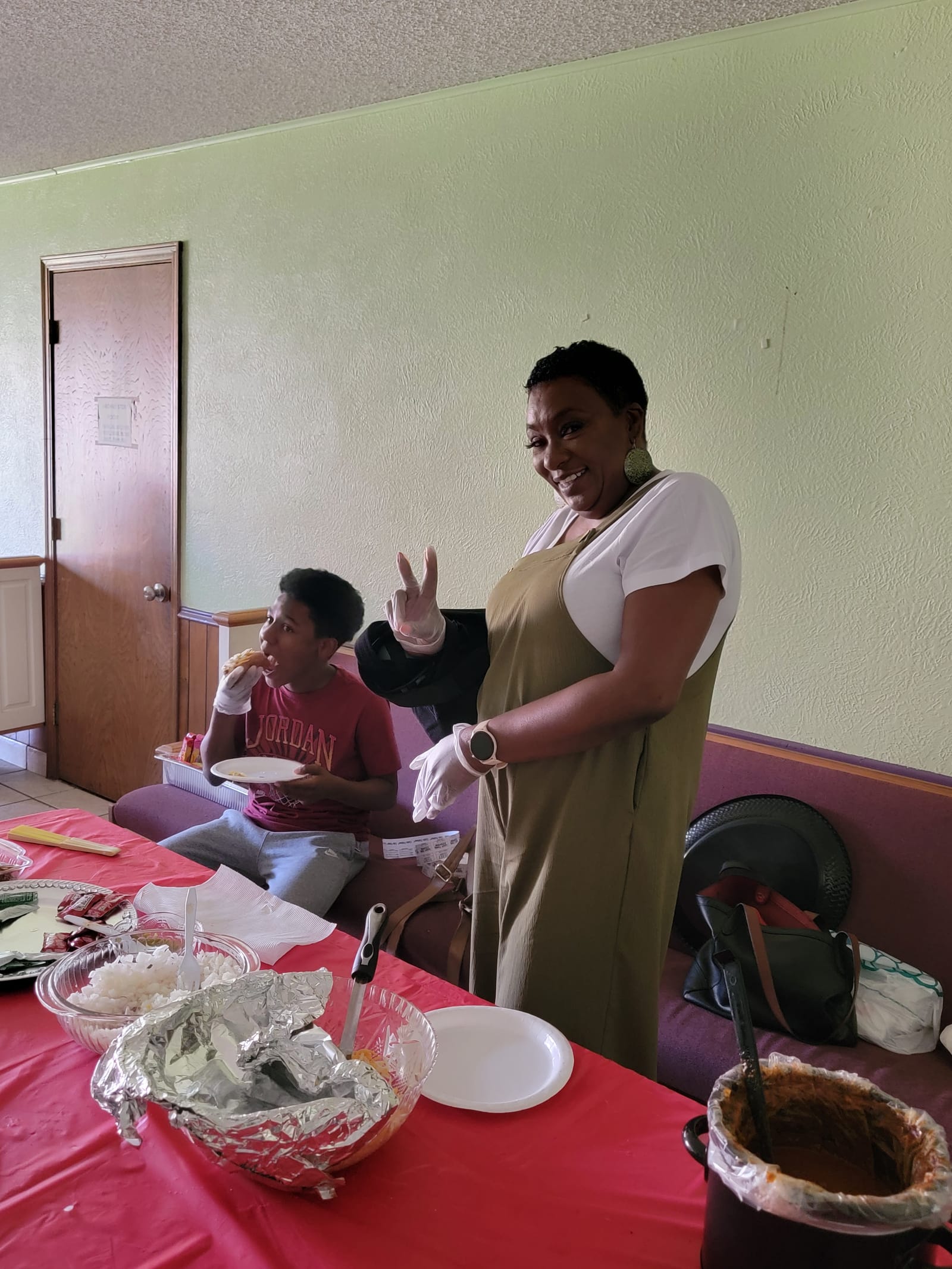 A Silver Saints volunteer in gloves serving a plate of food to a young guest