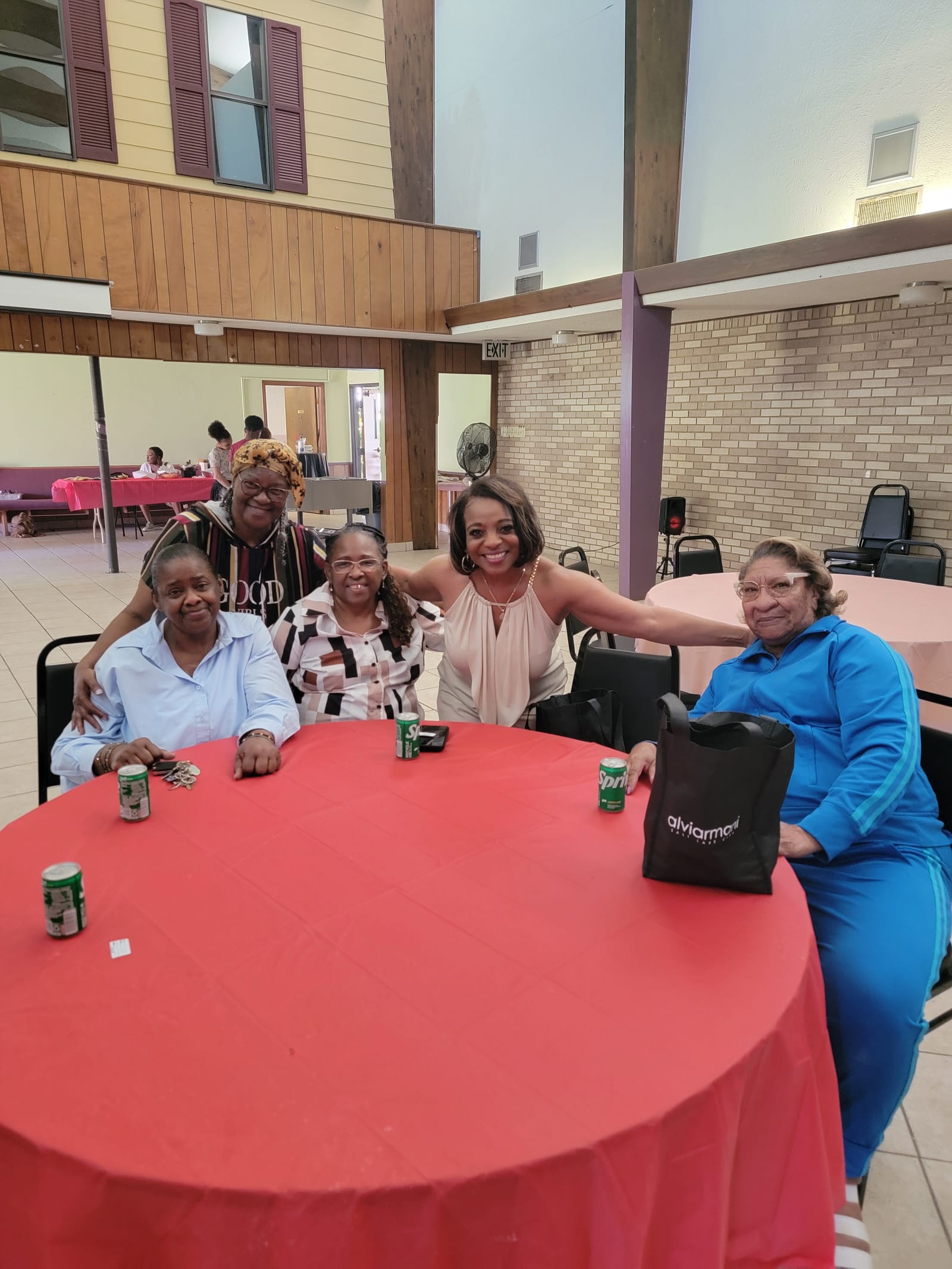 Seniors gathered around a red-covered table at a community hall event