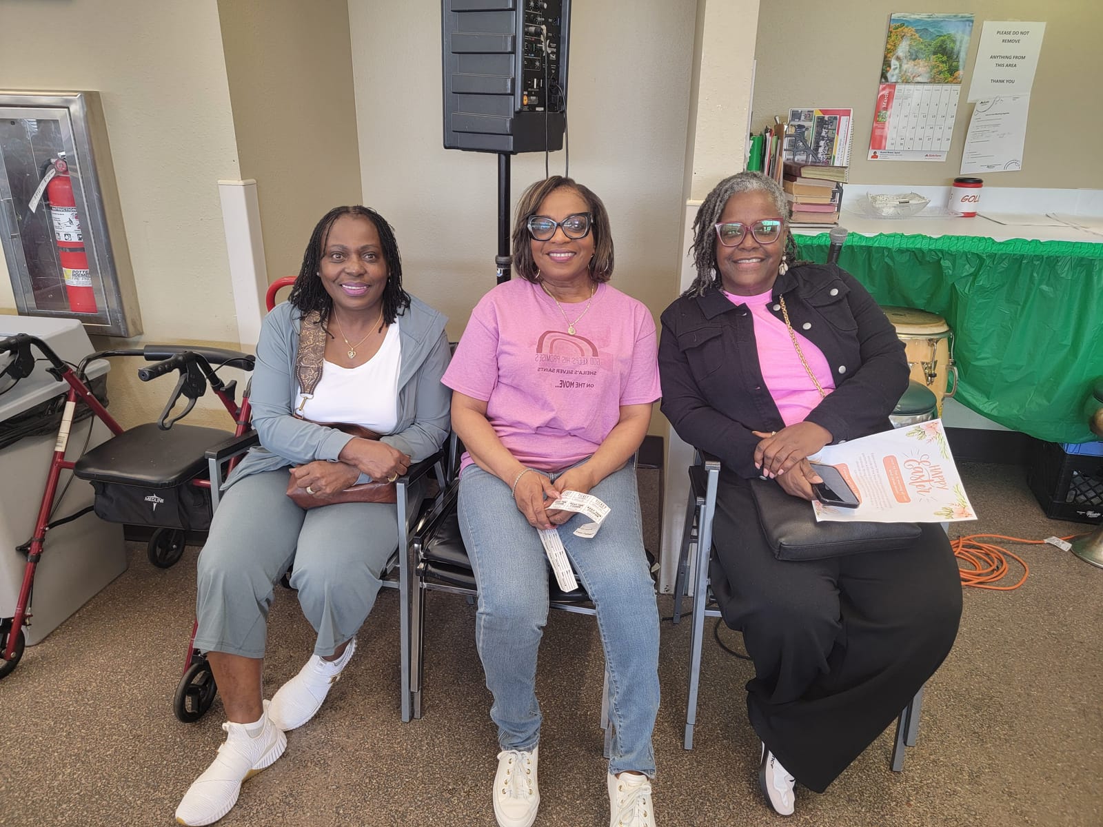 Three Silver Saints in pink event shirts seated together at a senior center