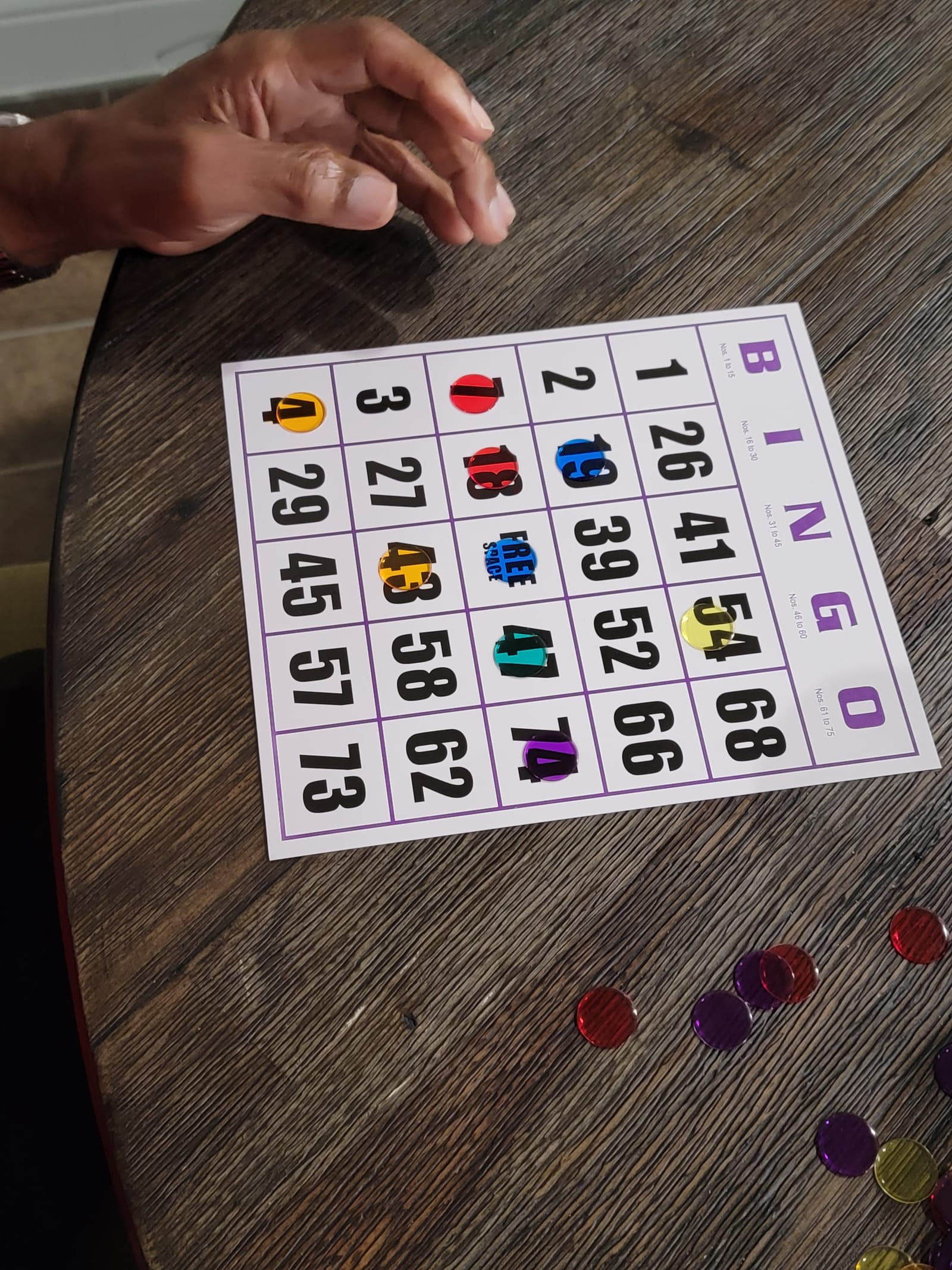 A bingo card with colored chips on a wooden table