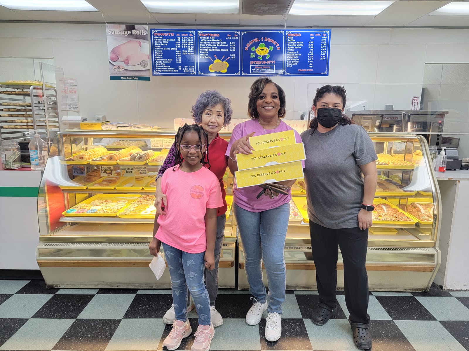 Sheila, a young Silver Saint and the team at Gospel 1 Donuts in DeSoto holding boxes of donated donuts
