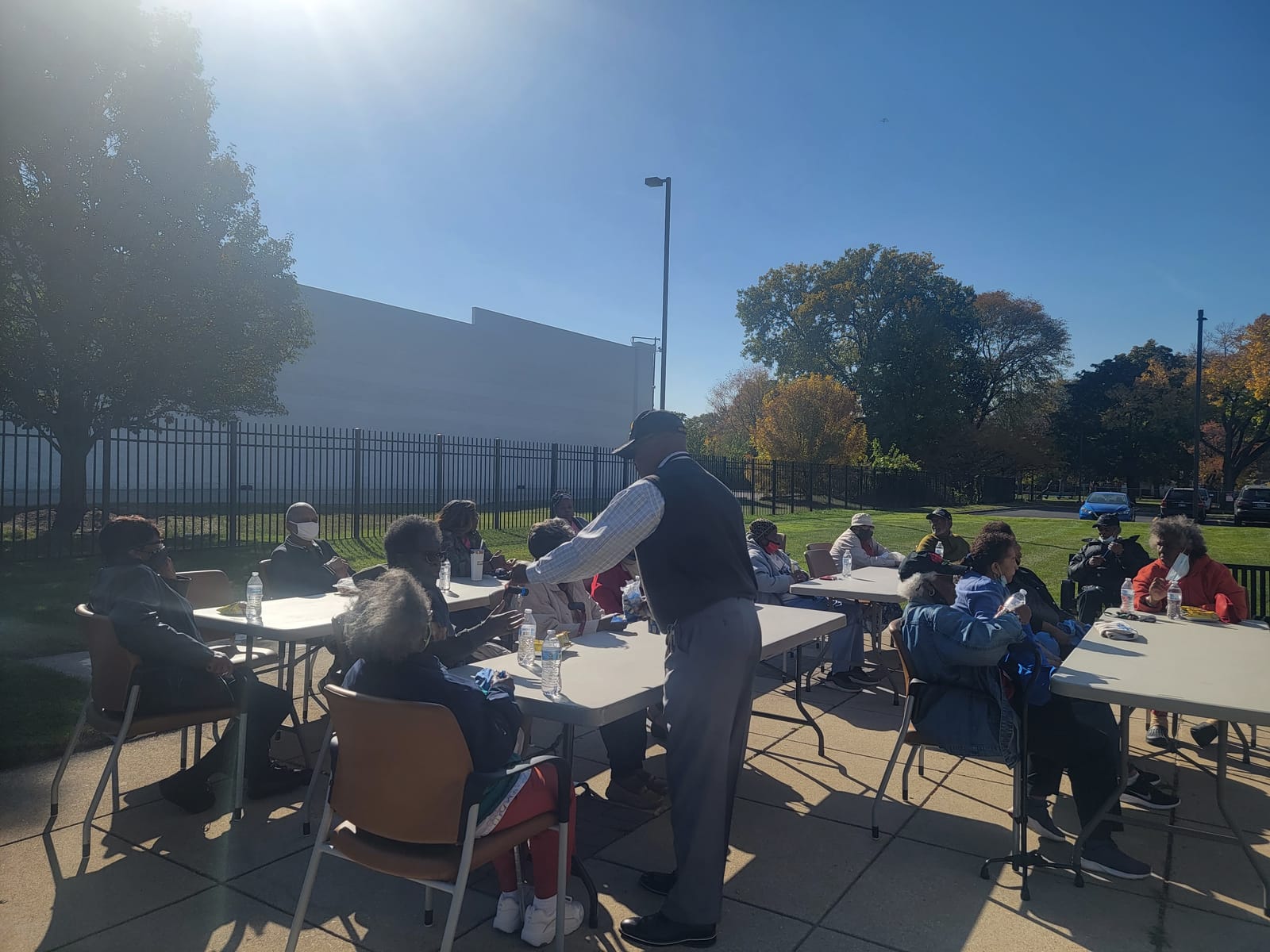 Seniors eating together at outdoor tables on a sunny day
